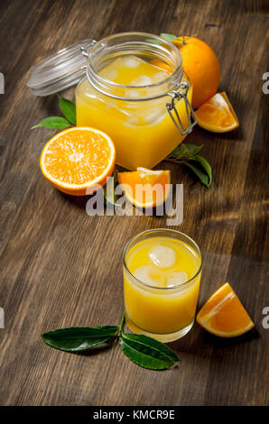 Freshly squeezed orange juice with slices of oranges. On a wooden table. Stock Photo
