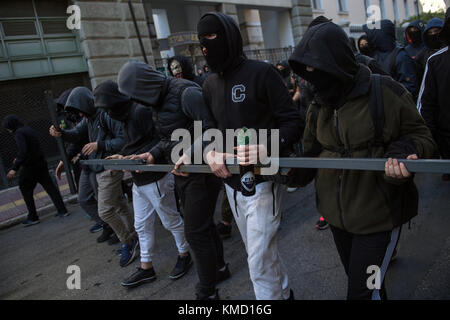 Athens, Greece. 6th Dec, 2017. Masked people can be seen partaking in a protest match in Athens, Greece, 6 December 2017. The ninth anniversary of the death of a 15 year old by police bullet was marked by riots. Some 200 masked persons threw stones against the police, devastated shops and cafés and lit some trash containers on fire. Credit: Angelos Tzortzinis/dpa/Alamy Live News Stock Photo