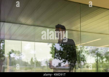 Businessman walking along window in office corridor Stock Photo