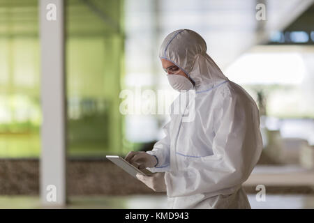 Scientist in clean suit using digital tablet Stock Photo