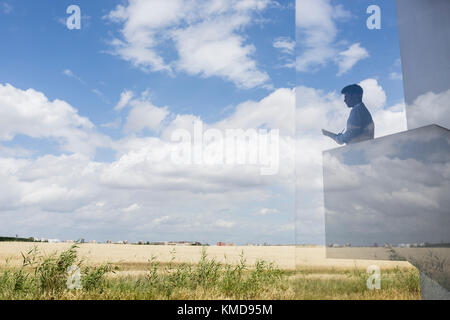 Silhouette businessman writing on modern balcony overlooking sunny blue sky and clouds Stock Photo