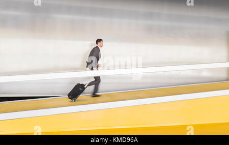Businessman running,pulling suitcase up airport ramp Stock Photo