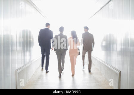 Business people walking in illuminated office corridor Stock Photo