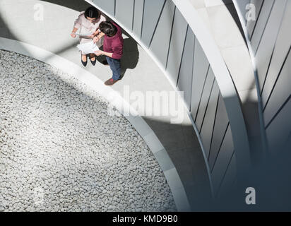 Businessman and businesswoman discussing paperwork in sunny courtyard Stock Photo