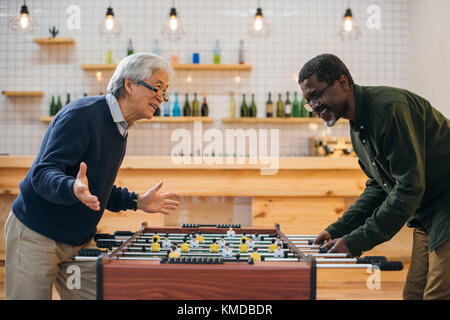 senior friends playing table football Stock Photo