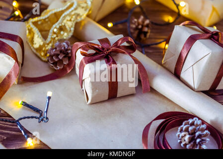 Close up christmas gift boxes in craft paper with satin ribbons and holiday decorations on the dark wooden background. Christmas and New year concept. Stock Photo