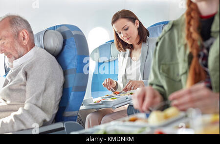 Woman eating dinner on airplane Stock Photo