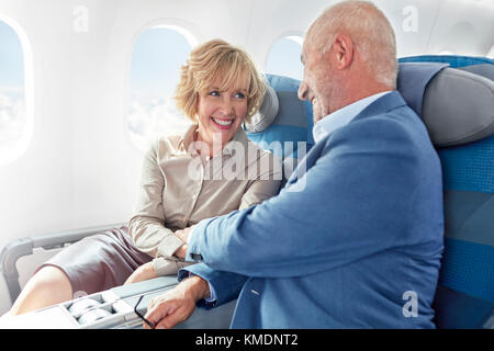 Affectionate mature couple holding hands on airplane Stock Photo