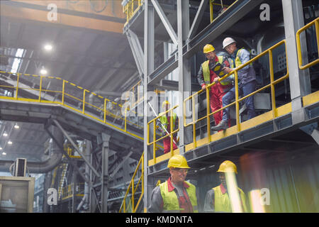 Steelworkers talking on platform in steel mill Stock Photo