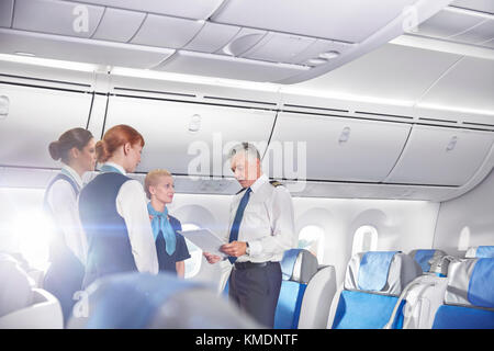 Pilot and flight attendants talking,preparing on airplane Stock Photo