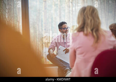 Smiling man talking in group therapy session Stock Photo