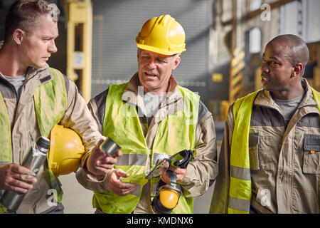 Steelworkers with insulated drink container taking coffee break in steel mill Stock Photo