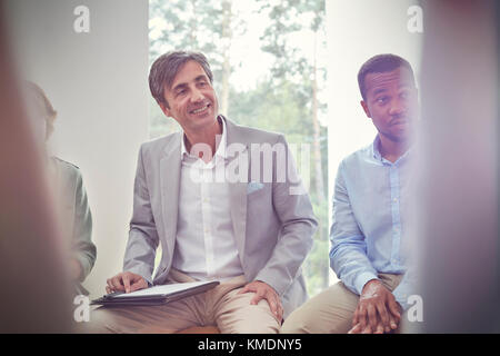 Smiling man listening in group therapy session Stock Photo