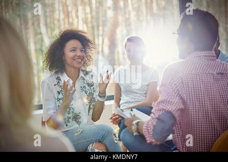 Smiling woman talking and gesturing in group therapy session Stock Photo