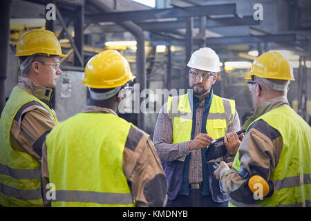 Supervisor talking with steelworkers in steel mill Stock Photo