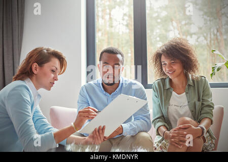 Female therapist with clipboard talking to couple in couples therapy session Stock Photo