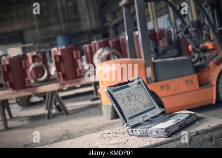 Digital blueprints on laptop in steel mill Stock Photo