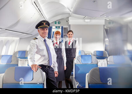 Portrait confident pilot and flight attendants on airplane Stock Photo