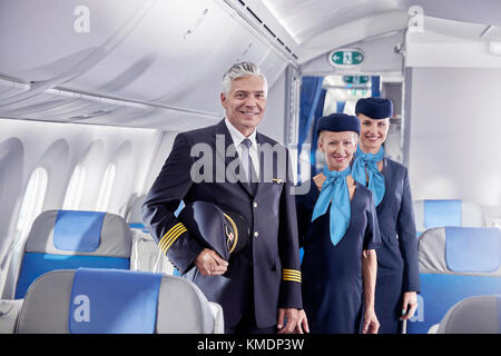 Portrait confident pilot and flight attendants on airplane Stock Photo