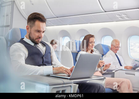Businessman working at laptop on airplane Stock Photo