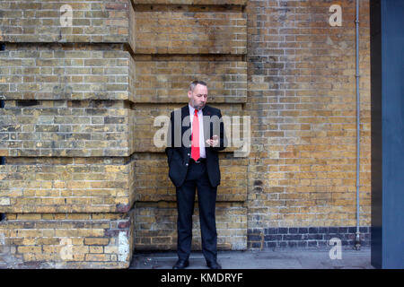 Man outside King's Cross train station using his mobile phone Stock Photo