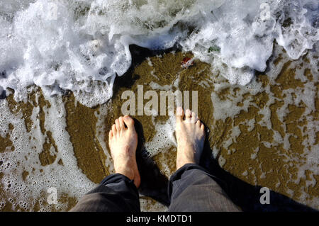 White feet being washed by Pacific Ocean waves on a beach in Vancouver. Stock Photo