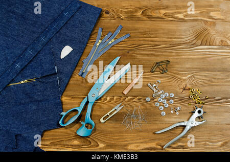jeans textile on wooden table background with scissors, zipper, chalk, pins Stock Photo