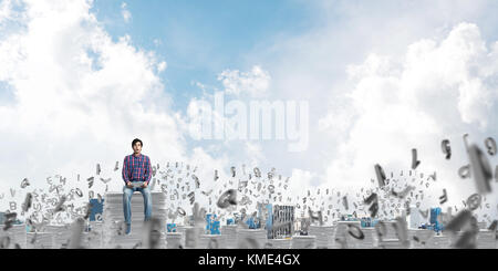 Attractive man sitting on pile of paper documents. Stock Photo