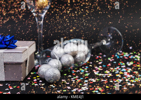 Happy new year concept with champagne glasses and gift or present on dark background with confetti Stock Photo