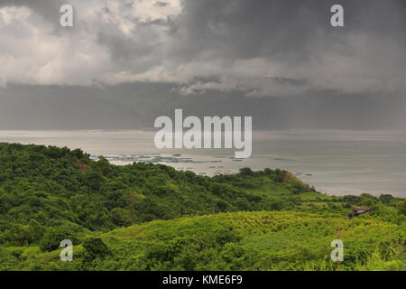 NW-ward view over Taal lake and fish cages for aquaculture to Tagaytay ridge from Volcano Island trail going up to Main Crater Lake under stormy sky a Stock Photo