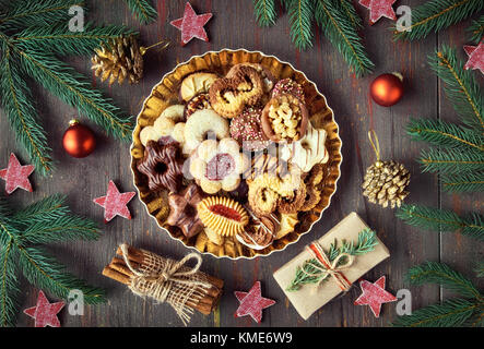 Plate of Christmas cookies on dark rustic background with Christmas decorations all around Stock Photo