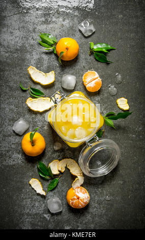 Fresh juice with mandarins, leaves, and ice. On a stone background. Top view Stock Photo