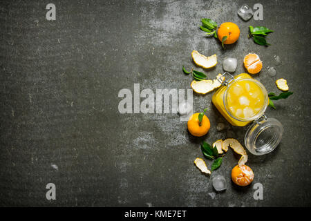 Fresh juice with mandarins, leaves, and ice. On a stone background. Free space for text . Top view Stock Photo