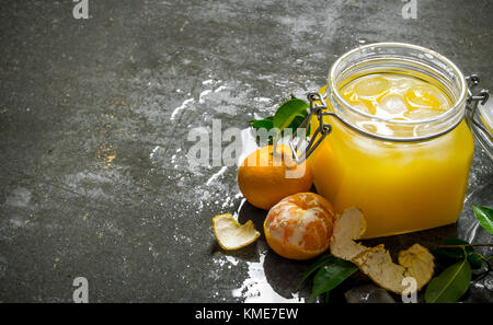Fresh juice with mandarins, leaves, and ice. On a stone background. Free space for text . Stock Photo