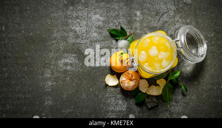Fresh juice with mandarins, leaves, and ice. On a stone background. Free space for text . Top view Stock Photo