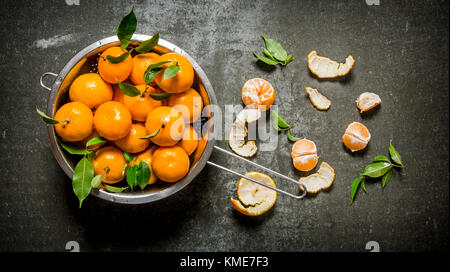 Mandarins with leaves in a saucepan. On a stone background. Top view Stock Photo