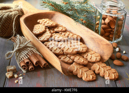 Almond cookies in larde wooden shovel with almond nuts in a glass jar, brown sugar and tied bunch of cinnamon sticks. Stock Photo