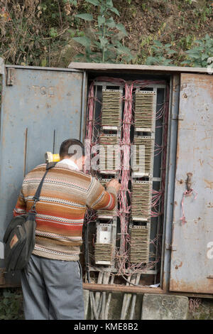 Telecommunications technician works on phone lines in street telephone wiring box at Mcleod Ganj India Stock Photo
