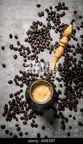 Coffee pot and roasted coffee around. On a stone background.