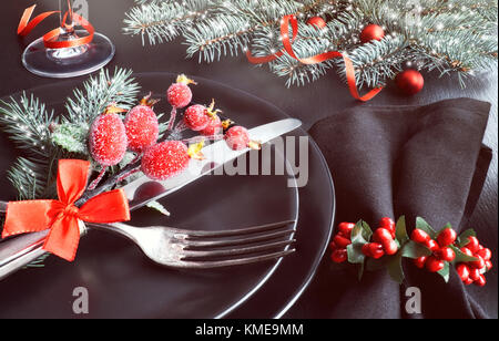 Christmas menu concept: black plates and cutlery with Christmas decorations on dark, close-up Stock Photo
