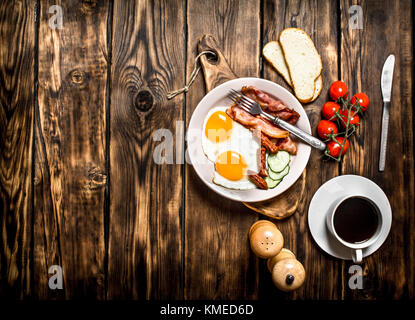 Fresh Breakfast with Cup of coffee, fried Beck with eggs and tomatoes. On a wooden table. Stock Photo