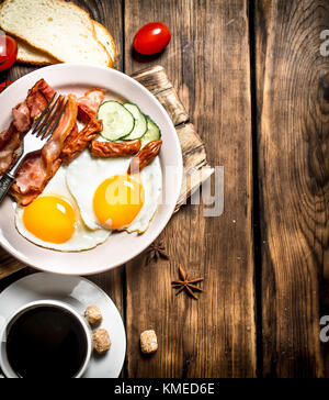 Fresh Breakfast with Cup of coffee, fried bacon with eggs and tomatoes. On a wooden table. Stock Photo