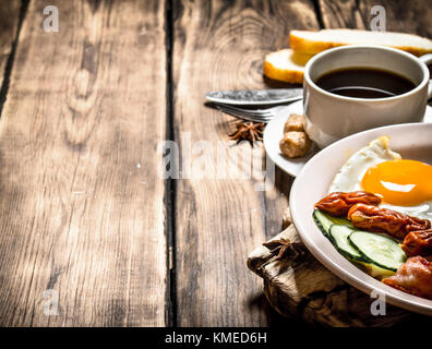 fresh Breakfast. Cup of coffee , fried bacon with eggs and smoked sausage. On wooden background. Stock Photo