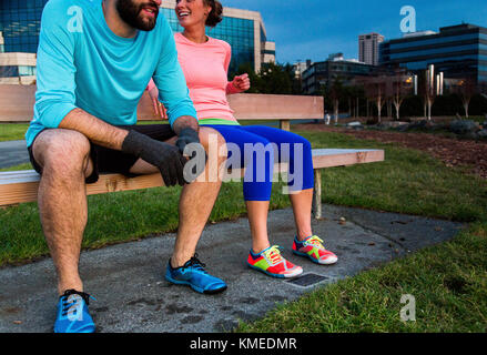 Two runners sit on a bench at dusk after a run in Seattle, WA. Stock Photo