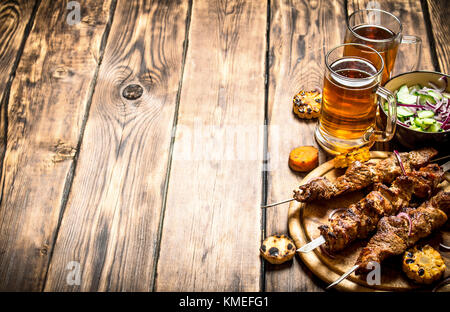 Pork kebab with beer and vegetables. On wooden background. Stock Photo