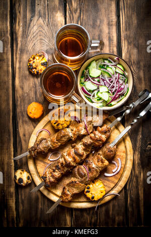 Pork kebab with beer and vegetables. On wooden background. Stock Photo