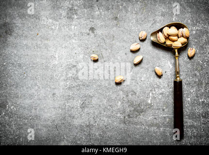 Pistachios in an old spoon. On the stone table Stock Photo
