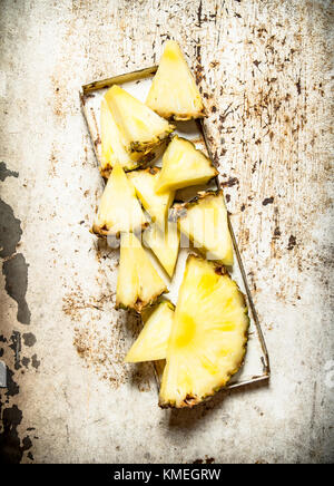 Slices of pineapple on the old tray. On rustic background . Stock Photo