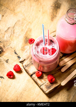 Berry smoothie raspberry with wooden sticks. On wooden background. Stock Photo