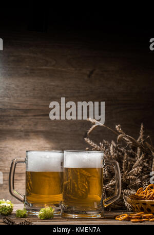 Cups beer, hops, pretzels,spikelets on empty wooden background Stock Photo